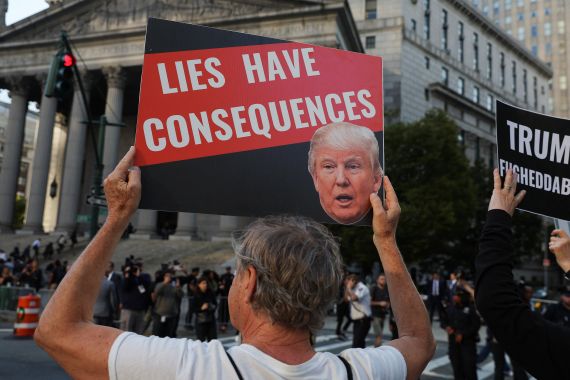 An anti-Trump demonstrator holds up a sign featuring an image of former U.S. President Donald Trump and the words 'lies have consequences'