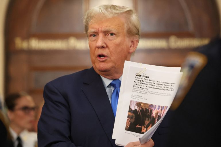 Trump holds up papers at a courthouse