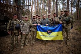 Ukraine&#39;s President Volodymyr Zelenskiy poses for a picture with service members as he visits a position of Ukrainian troops in a front line [Ukrainian Presidential Press Service via Reuters]
