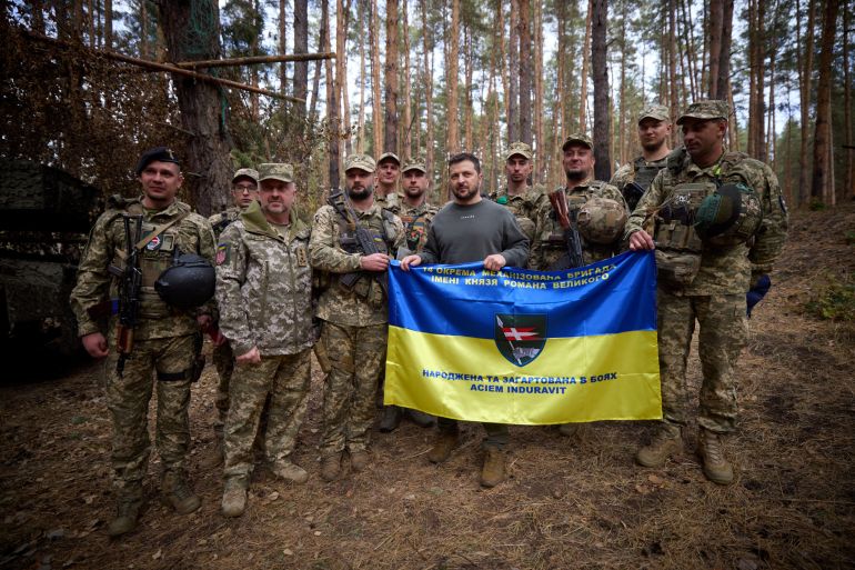 Ukraine's President Volodymyr Zelenskiy poses for a picture with service members as he visits a position of Ukrainian troops in a front line, amid Russia's attack on Ukraine, in an undisclosed location