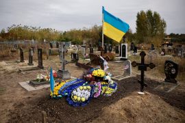 Wreaths are placed over the grave of Andriy Kozyr, a Ukrainian soldier whose wake was hit by a Russian military strike