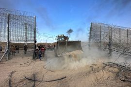 A bulldozer breaks the Israeli-built fence around Gaza on October 7, 2023 [Reuters/Mohammed Fayq Abu Mostafa]