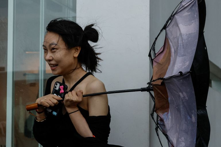A woman in Hong Kong tries to hold onto her umbrella as it turns inside out