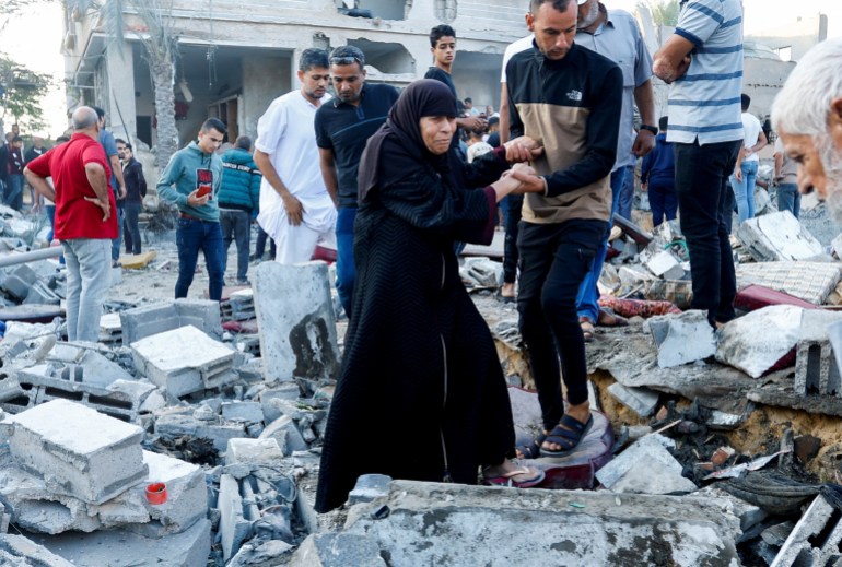 People walk on rubble in the aftermath of a strike amid the conflict with Israel in Khan Younis, in the southern Gaza Strip, October 12, 2023.