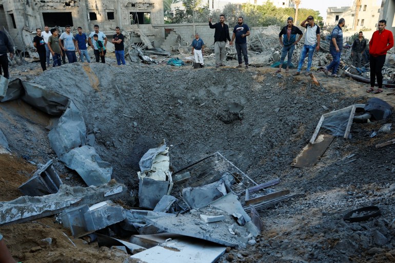 Palestinians look at the rubble of a house destroyed 