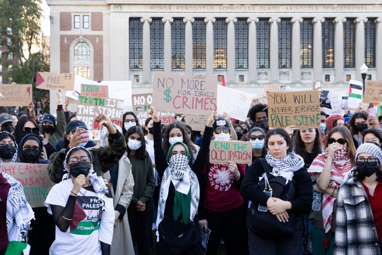 Standing in front of the colonnade of Columbia University's Butler Library, students hold up handwritten signs on cardboard to show support for the Palestinian cause.