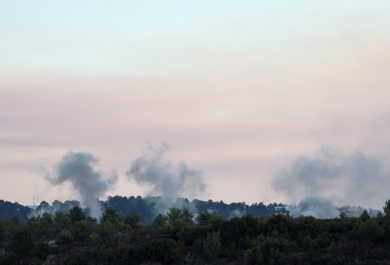 Three clouds of missile smoke rise above a forested horizon.