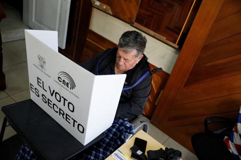 An elderly man sits behind a privacy screen to fill in his election ballot.