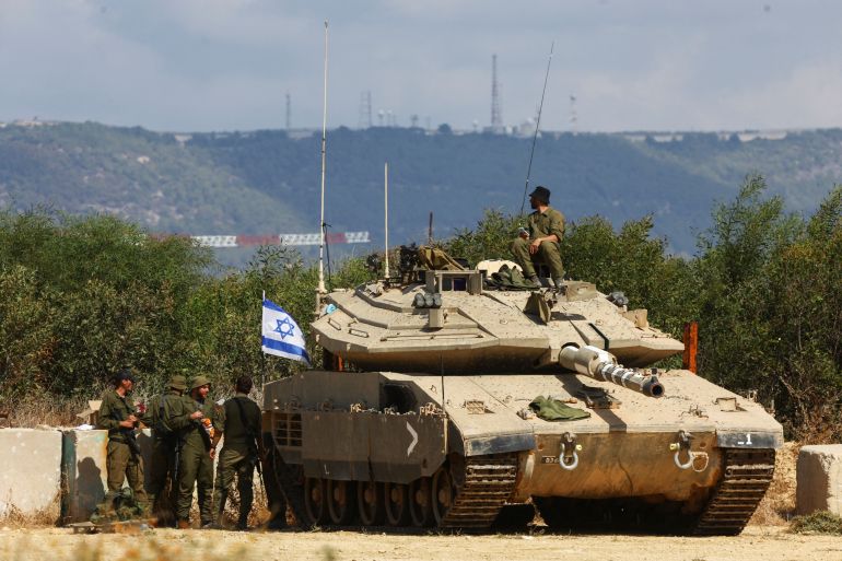 Israeli soldiers stand near a tank on Israel's border with Lebanon in the north