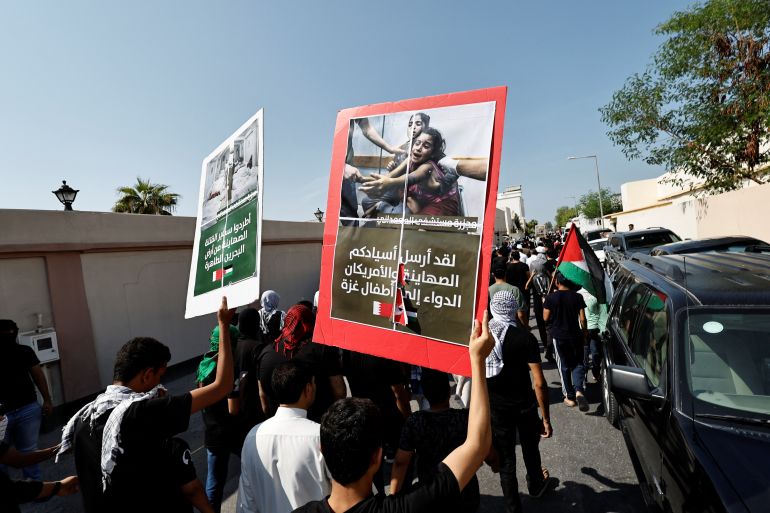Protesters holding photos of aftermath from Gaza raids as they march during a protest in support of Palestinians after Friday prayers in the village of Diraz, Bahrain