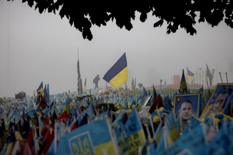 A man walks past Ukrainian flags at a memorial site commemorating fallen soldiers in Independence Square on a foggy morning, amid Russia's attack on Ukraine, in Kyiv, Ukraine, October 21, 2023