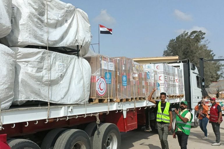 Membri e volontari della Mezzaluna Rossa egiziana si riuniscono accanto a un camion che trasporta aiuti umanitari mentre attraversa il valico di Rafah dal lato egiziano.