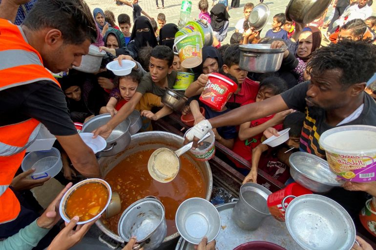 People in Gaza with bowls outstretched as they wait for food