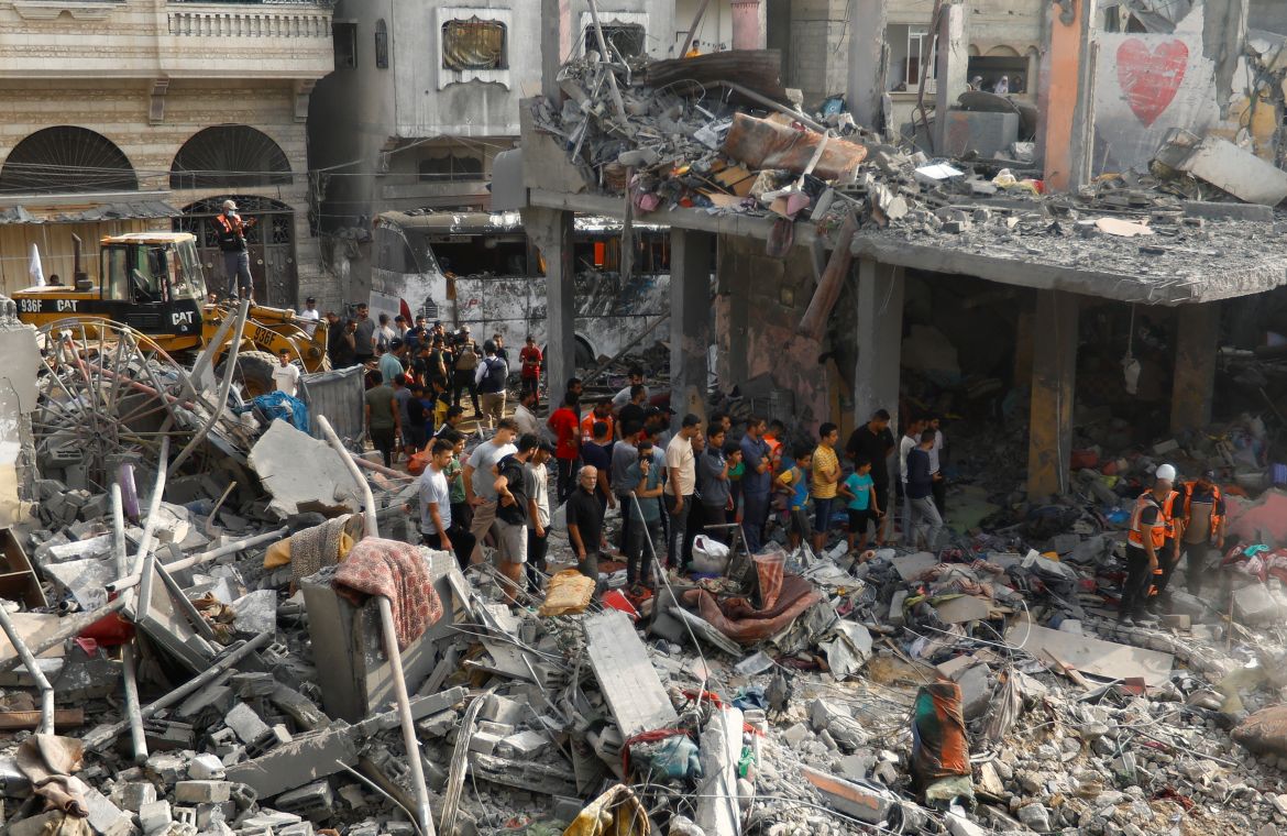 Palestinians look on during a search for casualties at the site of Israeli strikes on houses, in Khan Younis