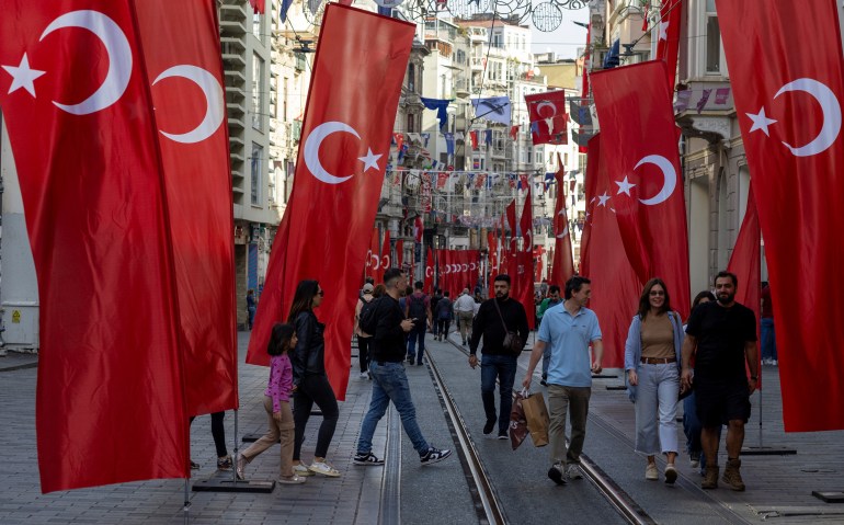 People walk along Istiklal Avenue, decorated with Turkish national flags, as Turks will celebrate the centenary of their modern republic's founding on Sunday, in Istanbul, Turkey, October 27, 2023. REUTERS/Umit Bektas