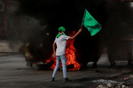 A person holds a flag during clashes between Israeli forces and Palestinians