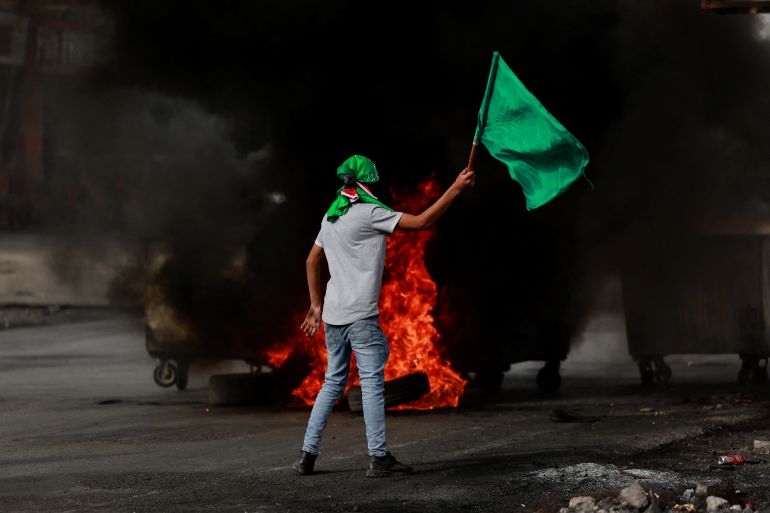 A person holds a flag during clashes between Israeli forces and Palestinians