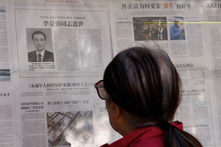 A woman looking at an official newspaper on Li Keqiang's death