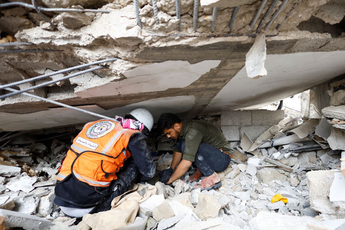 An Emergency worker and a Palestinian man check the damage at the site of Israeli strikes on houses, amid the ongoing conflict between Israel and Palestinian Islamist group Hamas, in Khan Younis