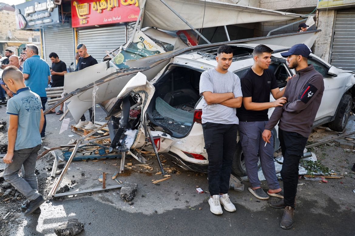 Palestinians stand on a damaged street, following an Israeli raid in Jenin,