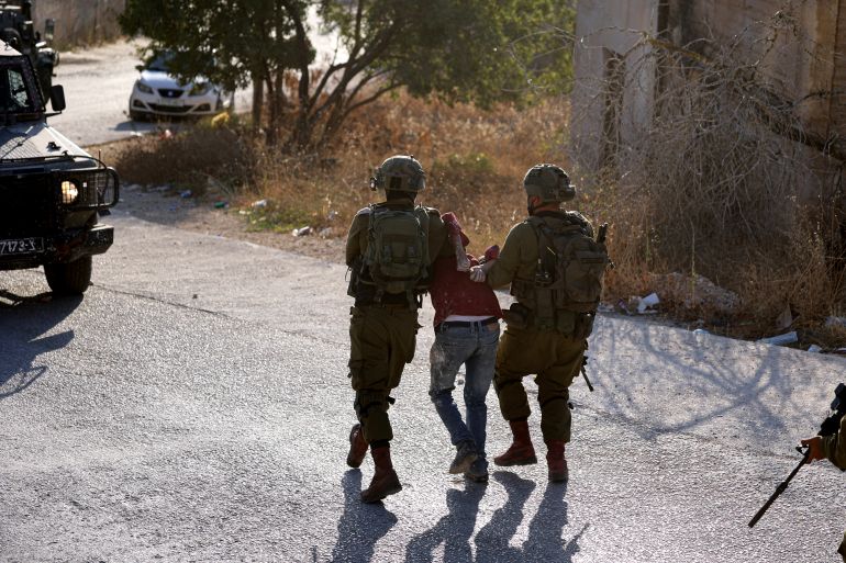 Israeli soldiers arrest a Palestinian man during a search operation in the occupied West Bank