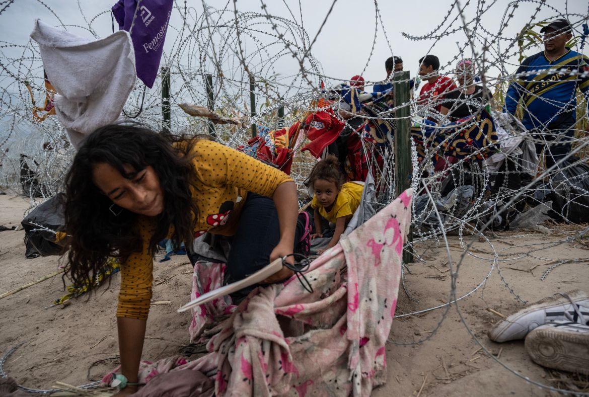 Migrants from Venezuela crawl through a hole in the razor wire to cross into Eagle Pass, Texas