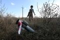 A deminer of the charitable fund 'Demining of Ukraine' stands next to an unexploded shell in the field near the town of Derhachi, Kharkiv region, on October 1, 2023. (Photo by SERGEY BOBOK / AFP)