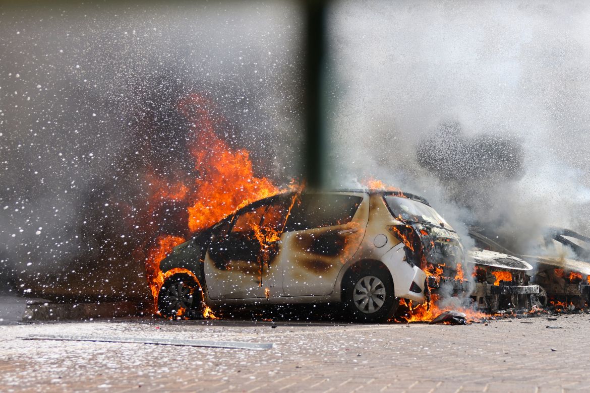 Cars are seen on fire following a rocket attack from the Gaza Strip