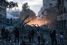 People walk atop the rubble of a tower destroyed in an Israeli air stike in Gaza City