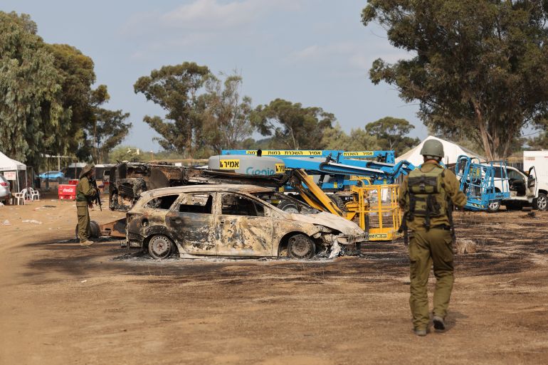 Israeli troops inspect the ravaged site of the weekend attack on the Supernova desert music Festival