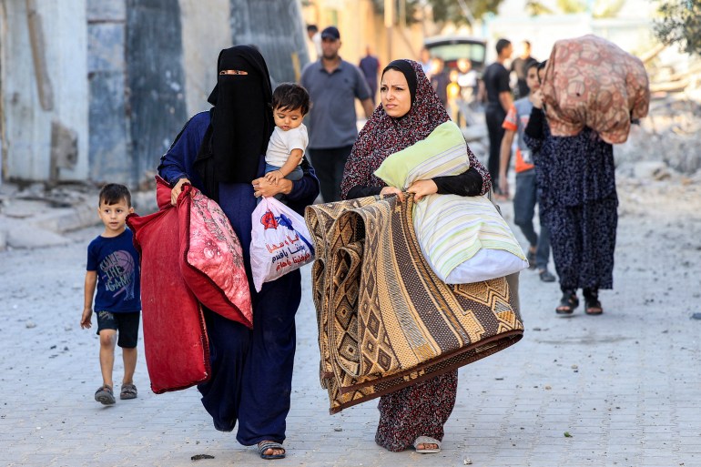 Palestinian women walk with children and belongings as they flee an area in the aftermath of an Israeli air strike in Rafah in the southern Gaza Strip 