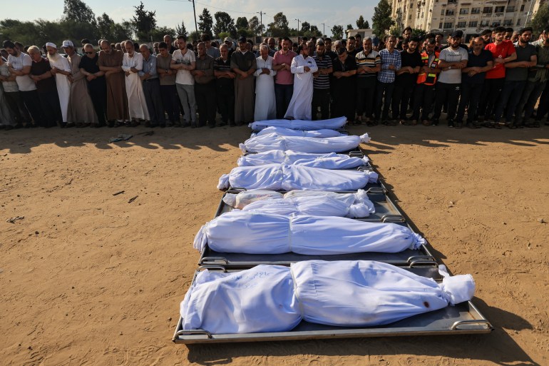 Mourners pray over the shrouded bodies of members of the Agha family, killed in an Israeli strike in Khan Yunis in the Gaza Strip,