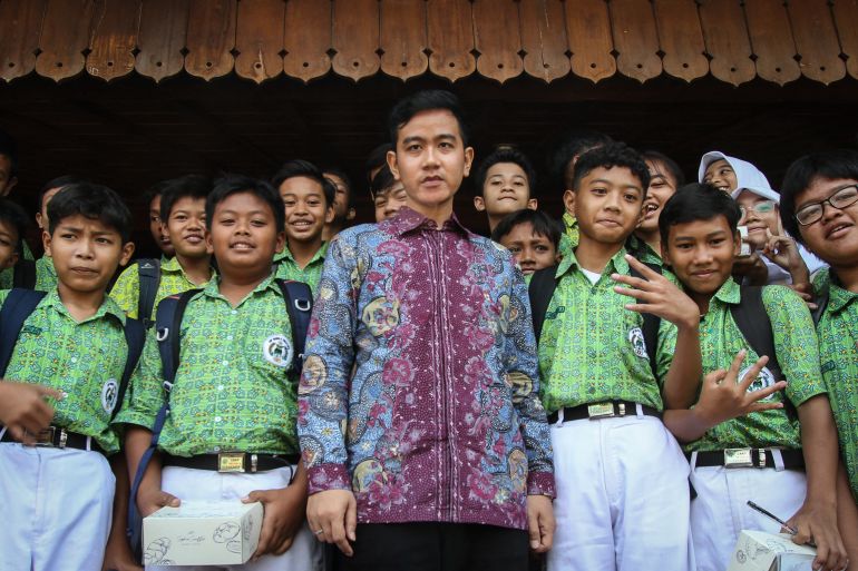 Gibran Rakabuming Raka, the son of Indonesian President Joko Widodo. He is wearing a batik shirt. And there are schoolchildren standing behind him.