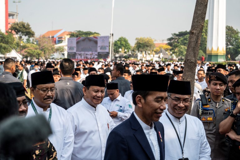 Prawbowo with Jokowi at an event on Sunday. They are walking outside. Both are dressed in white shirts.
