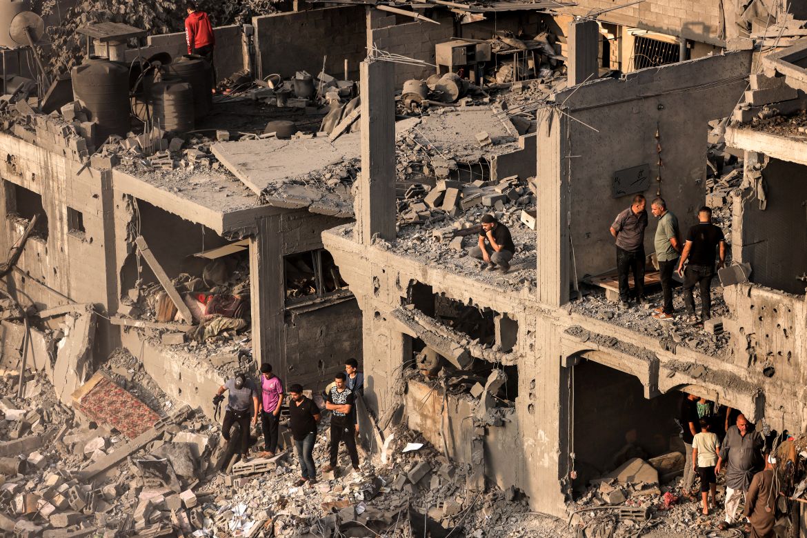 People search for survivors and the bodies of victims through buildings that were destroyed during Israeli bombardment, in Khan Yunis