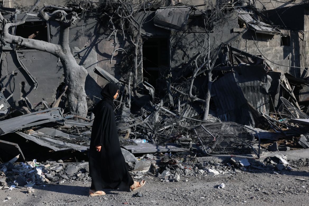 A Palestinian woman walks past building rubble