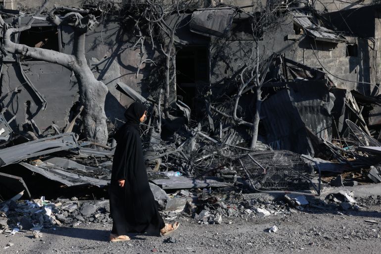 Una donna palestinese passa davanti alle macerie di un edificio