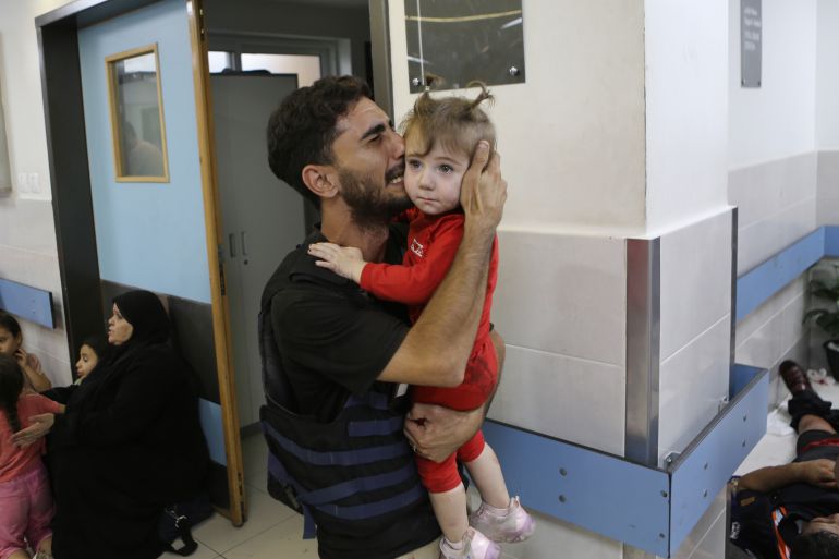 Sameh Murad cries as he holds his daughter Mayar after she survived the Israeli targeting on convoys of people leaving for the southern Gaza Strip