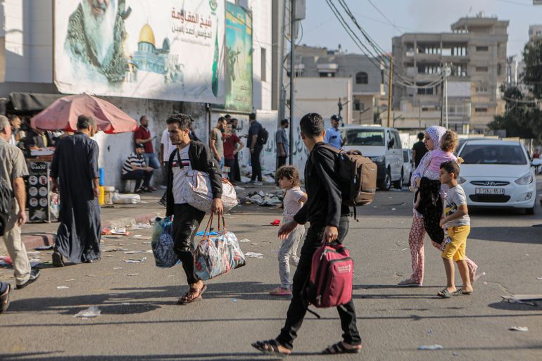 Men carry small bags as they leave their homes, some already displaced since the beginning of the war after taking refuge in UNRWA schools 