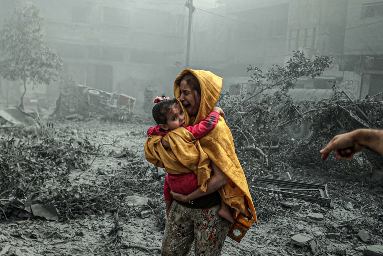 A woman holding a girl reacts after Israeli airstrikes hit Ridwan neighborhood of Gaza City, Gaza on October 23, 2023. (
