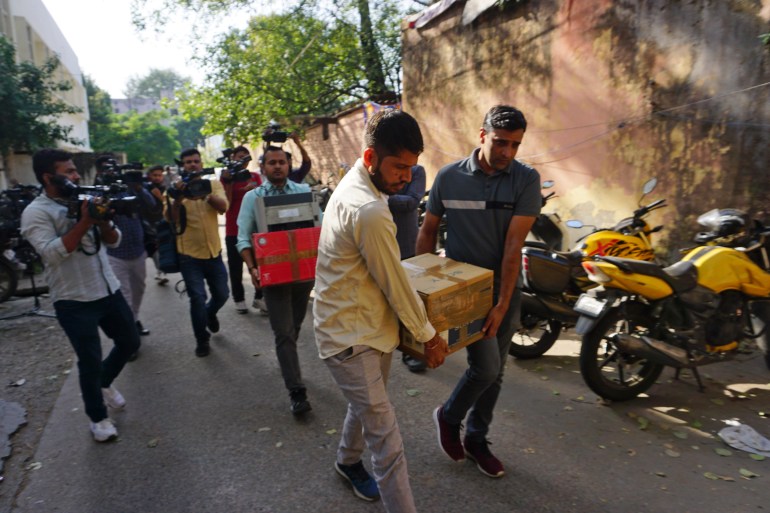 Security officers carry boxes of material confiscated after a raid at the office of NewsClick in New Delhi, India, Tuesday, Oct. 3, 2023. Indian police raided the offices of the news website that's under investigation for allegedly receiving funds from China, as well as the homes of several of its journalists, in what critics described as an attack on one of India's few remaining independent news outlets.