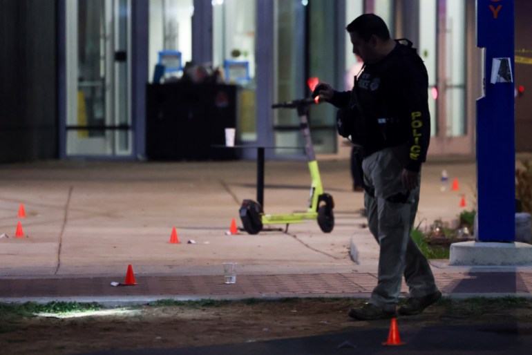 A police officer searches for evidence in front of a building at Morgan State University
