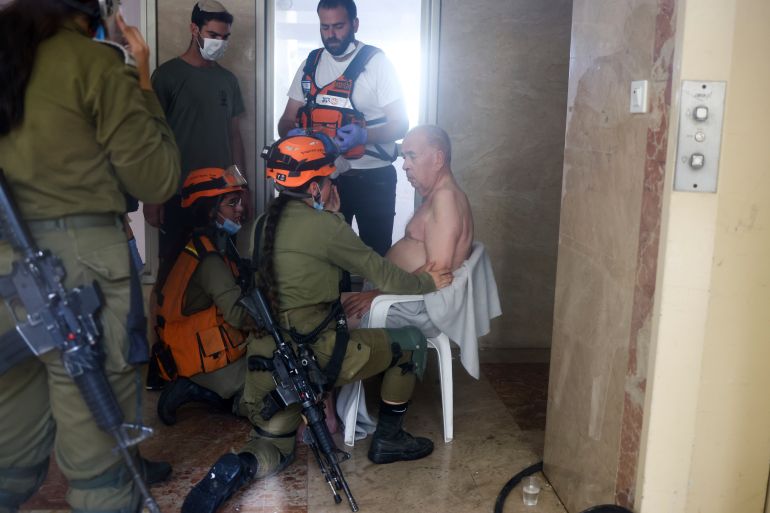 Israeli medics and security forces treat a man at a site hit by a rocket fired from the Gaza Strip, in Ashkelon