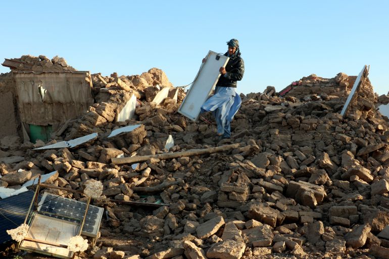 An Afghan man removes debris after an earthquake in Zenda Jan district in Herat province, of western Afghanistan