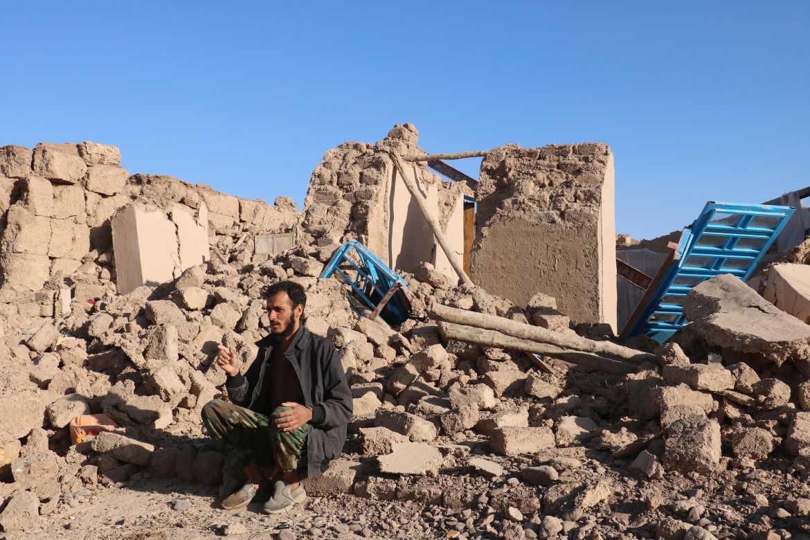 An Afghan man sits in a courtyard of a destroyed home after an earthquake in Zenda Jan district in Herat province