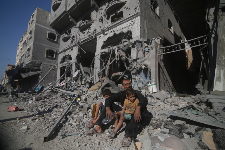 Palestinians sit outside their house following Israeli airstrikes in Rafah refugee camp, southern Gaza Strip