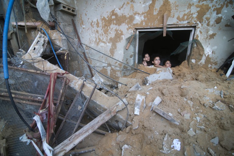 Palestinian children look at the building of the Zanon family, destroyed in Israeli airstrikes in Rafah, Gaza Strip