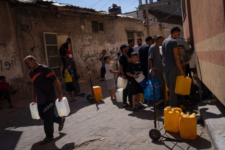 Palestinians collect water from a water tap, amid drinking water shortages, in Khan Younis, Gaza Strip, Sunday, Oct, 15, 2023. Israel cut off water to Gaza after a Hamas attack last week killed 1,300 people and Israel's retaliatory strikes killed more than 2,300 Palestinians.