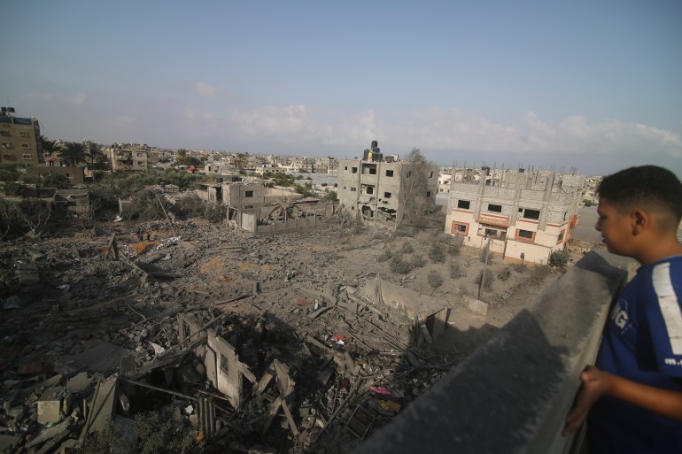 Un bambino palestinese guarda gli edifici distrutti domenica dal bombardamento israeliano sulla Striscia di Gaza a Rafah