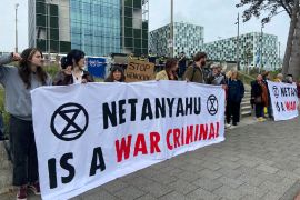 Activists hold up a banner denouncing Israeli Prime Minister Benjamin Netanyahu as they demonstrate at the entrance of the International Criminal Court in The Hague, Netherlands [File: Aleks Furtula/AP Photo]